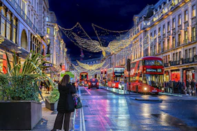 A london street decorated with christmas lights at night.