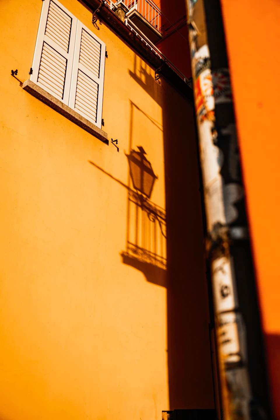 Narrow street with orange building and black pole in striking contrast against cool background