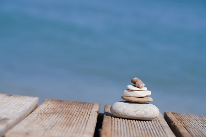 Stack of balanced stones on wooden planks by the sea.