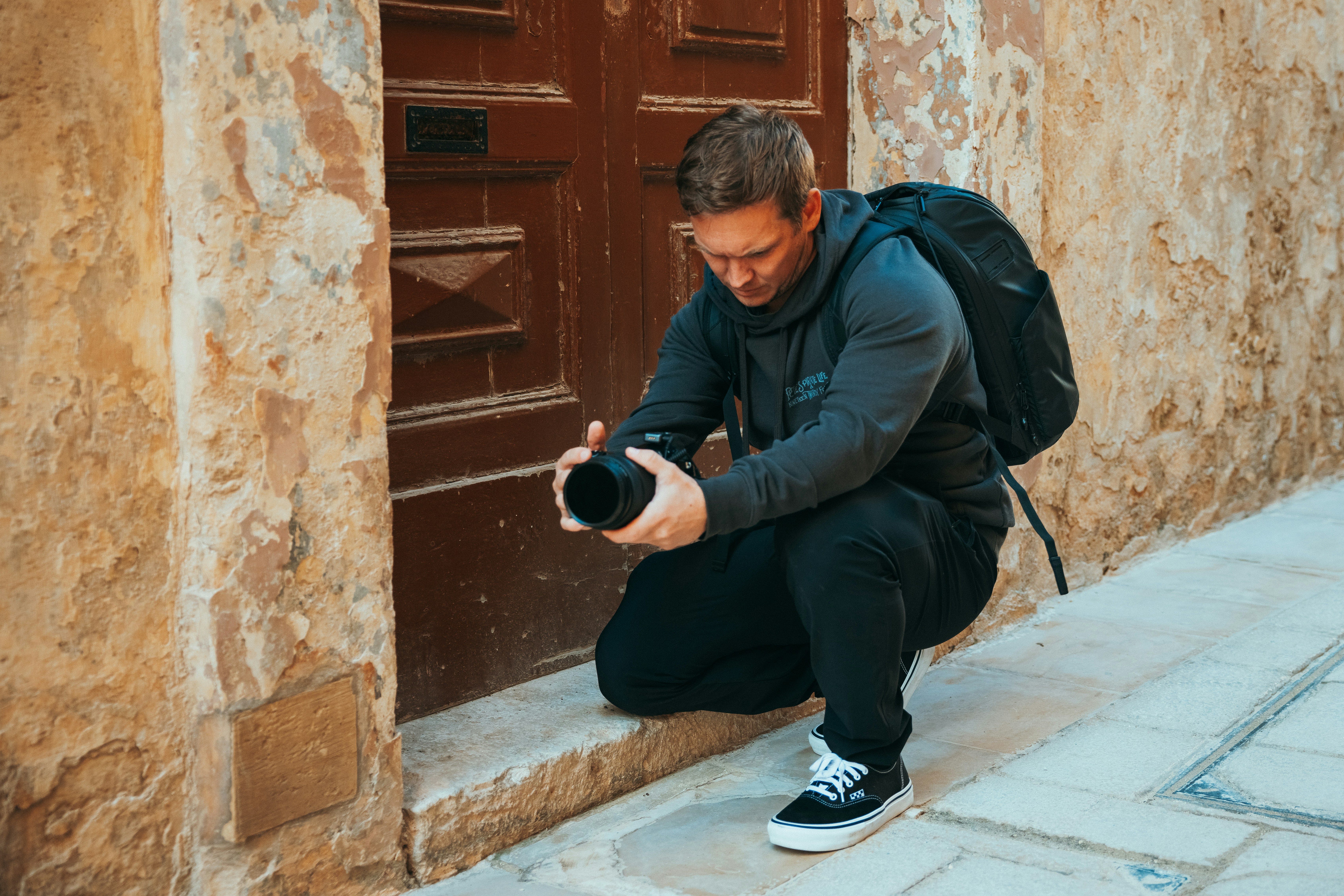 Man crouching, holding camera, taking picture