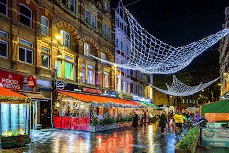 City street at night with illuminated buildings and decorations.