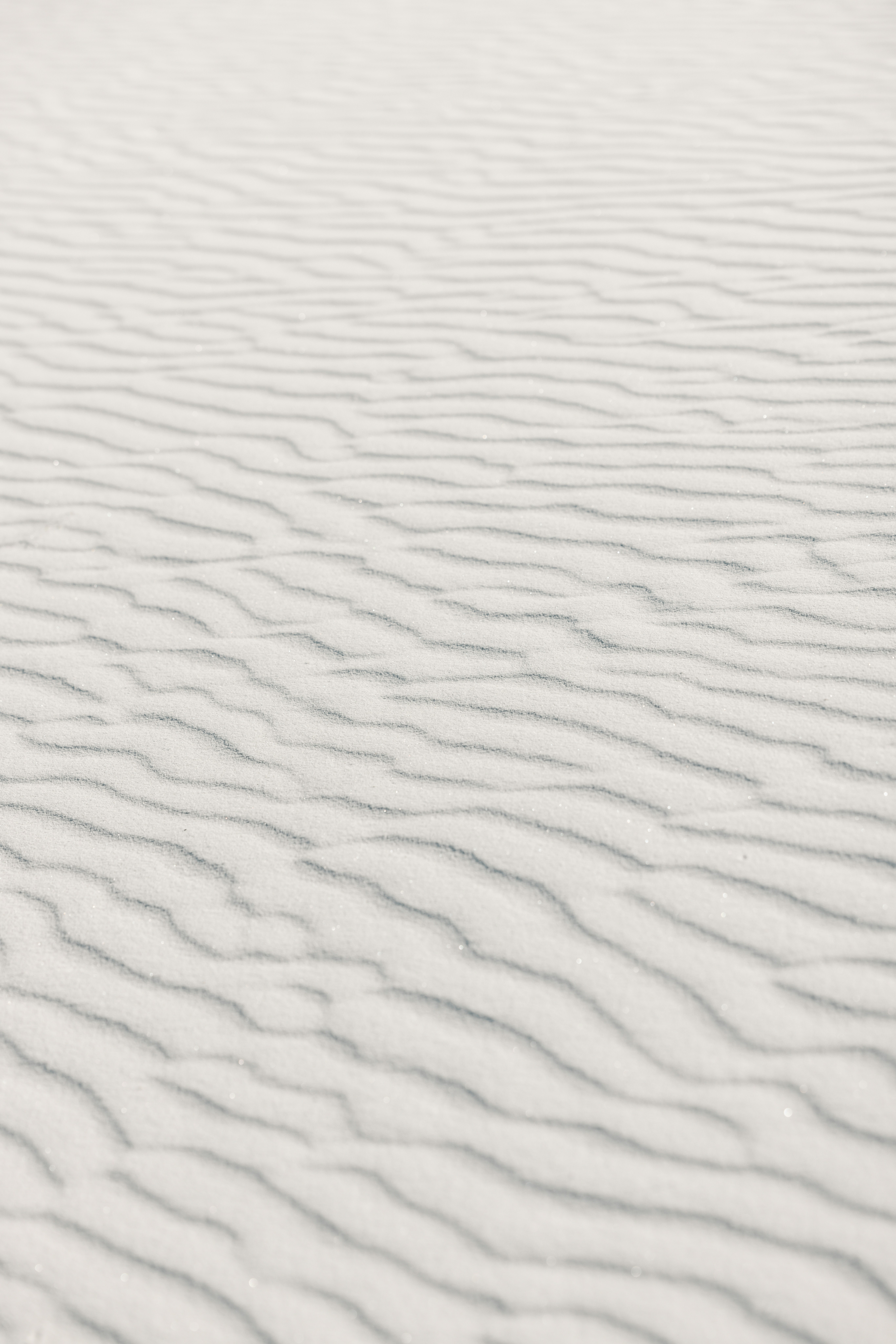 Rippled white sand dunes under bright sunlight