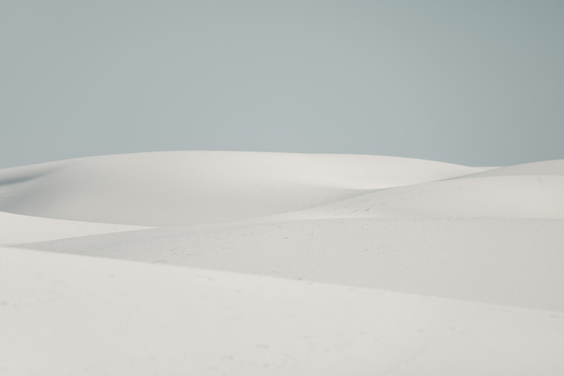 Soft white sand dunes under a pale sky