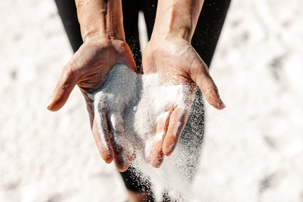 Hands holding and letting sand fall through.