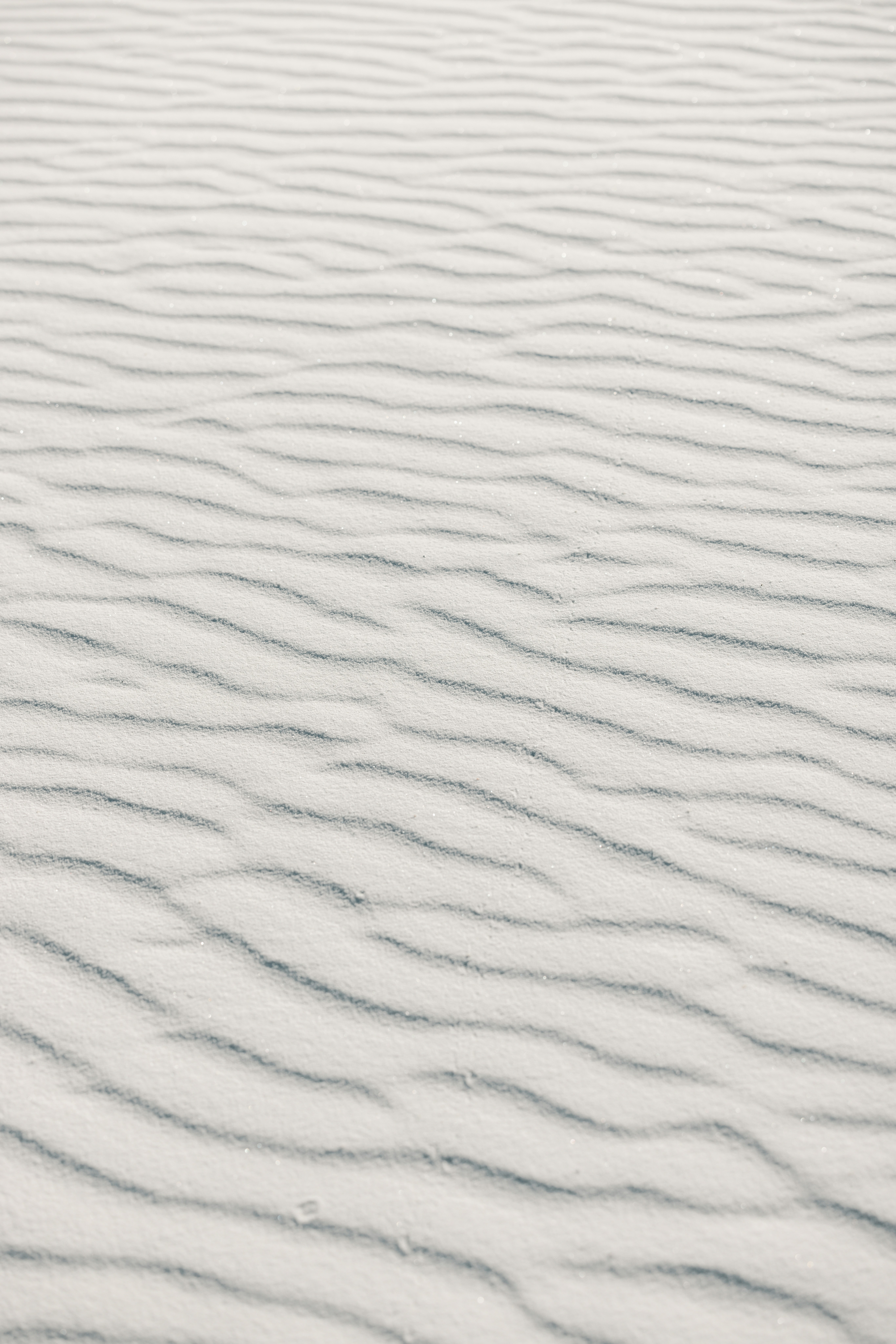 Rippled white sand dunes under a bright sky
