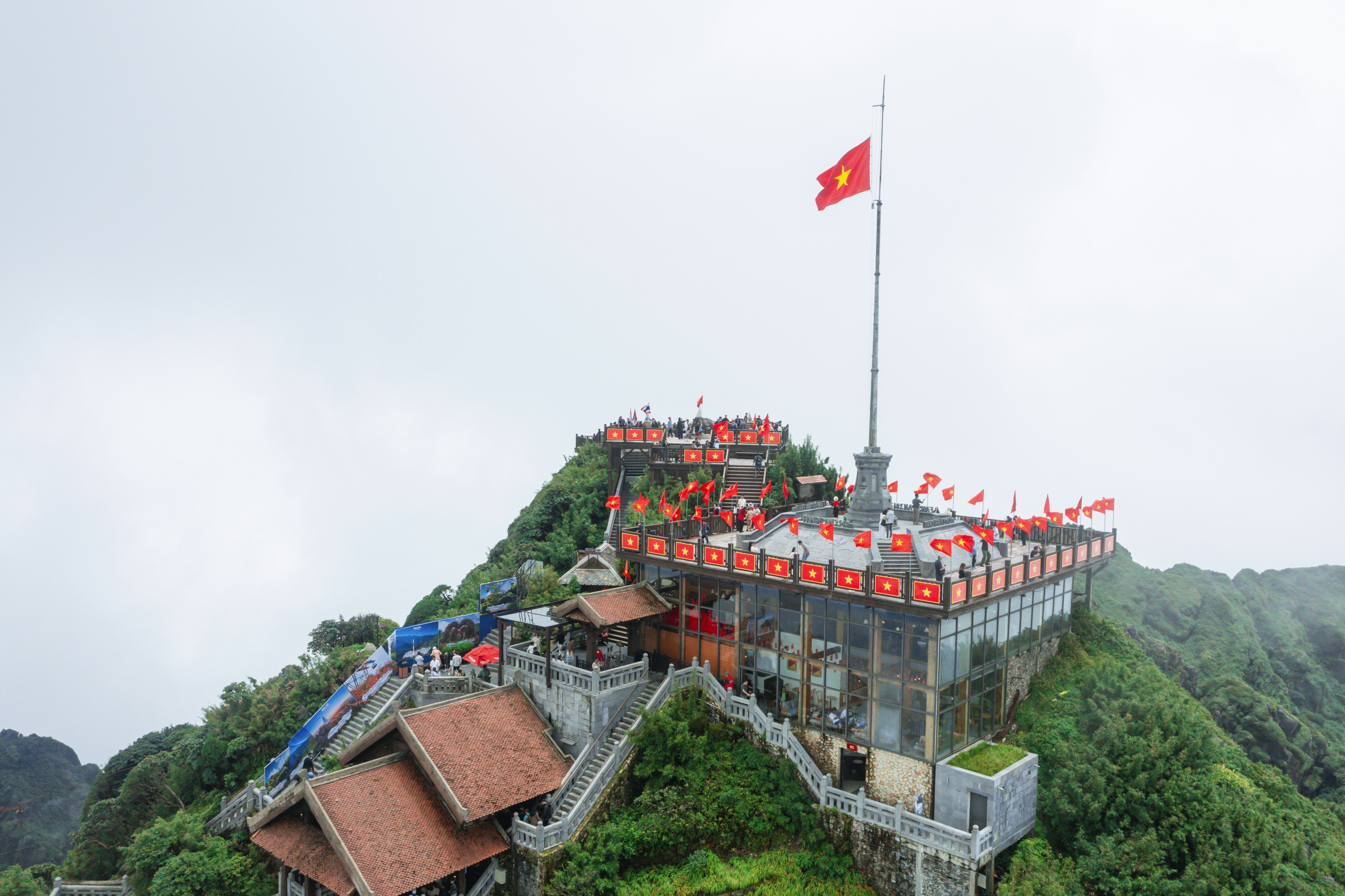 Temple complex on a misty mountain peak with vietnamese flag.