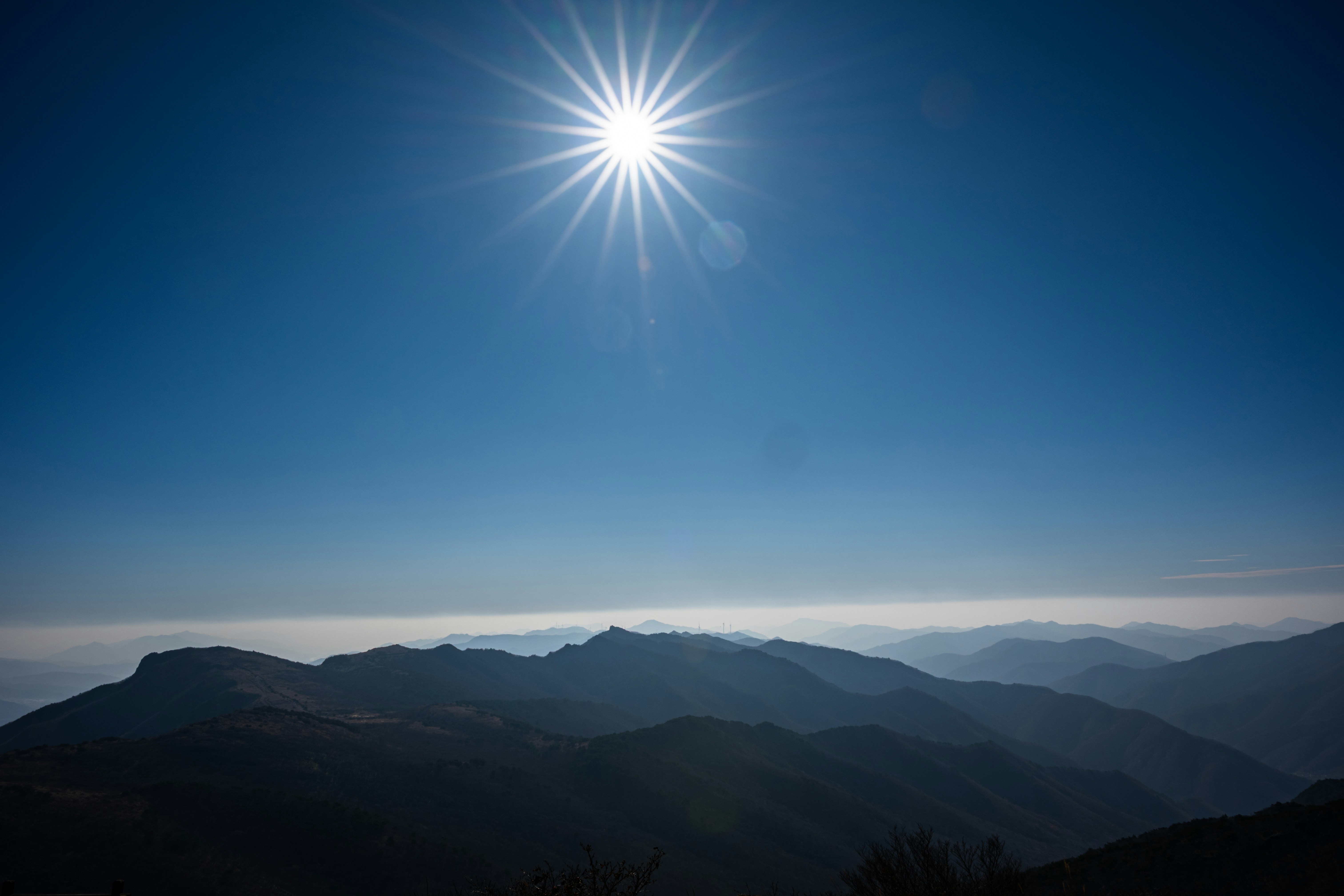 Helle Sonne über silhouettiertem Gebirge unter klarem Himmel