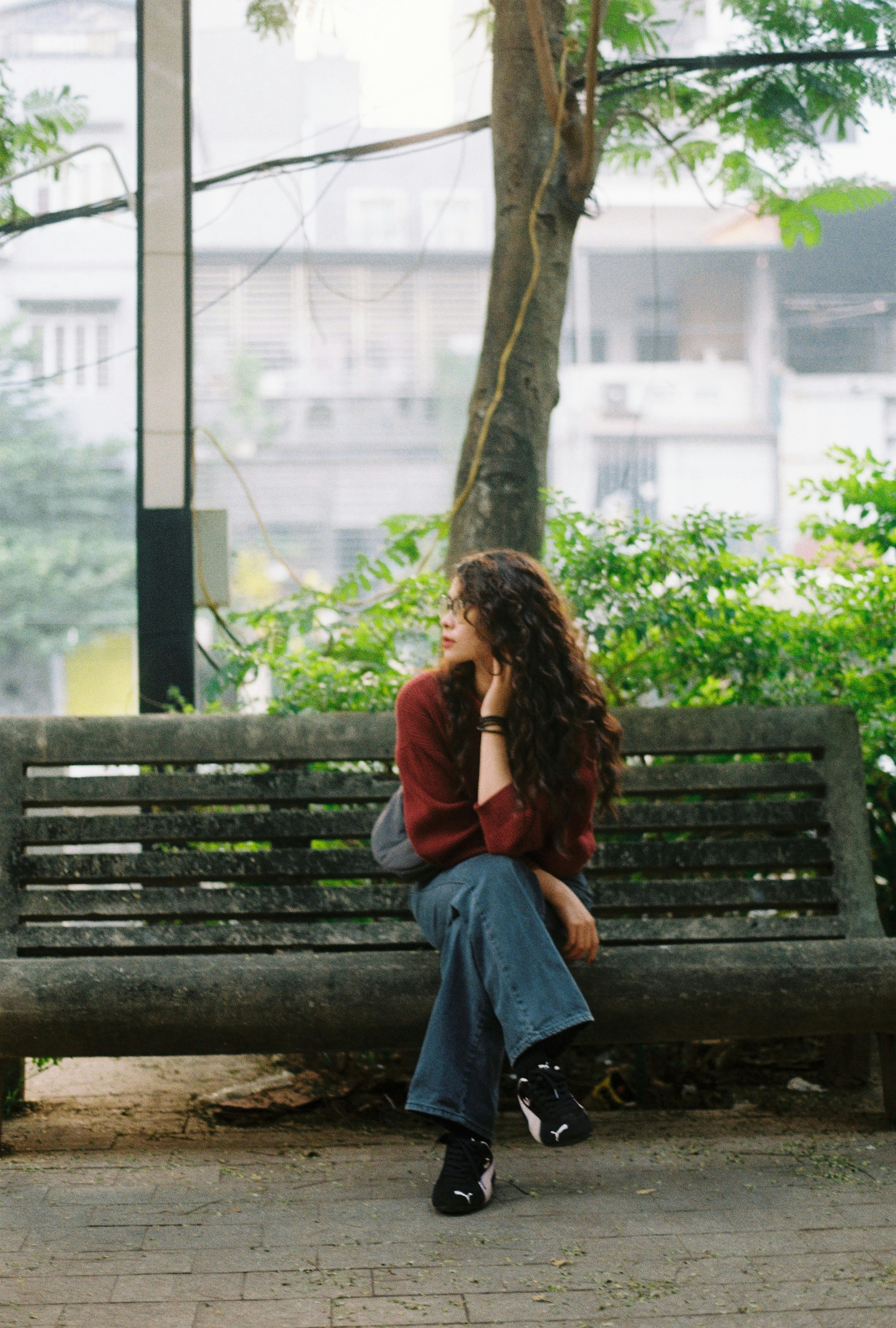 Woman with curly hair sitting on a park bench.