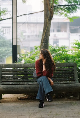 Woman with curly hair sitting on a park bench.