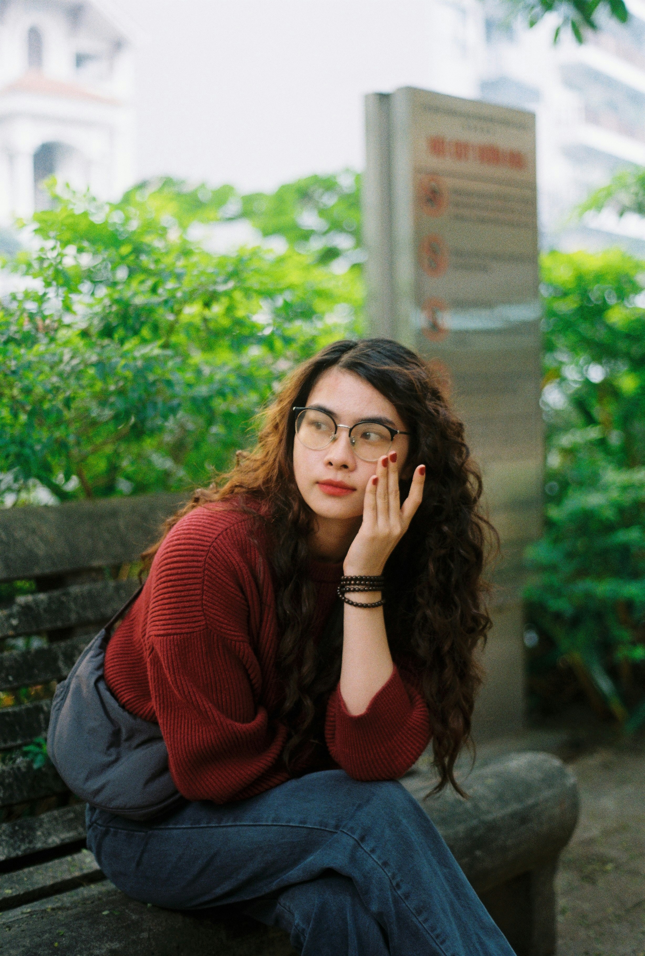 A young woman with curly hair on a bench.