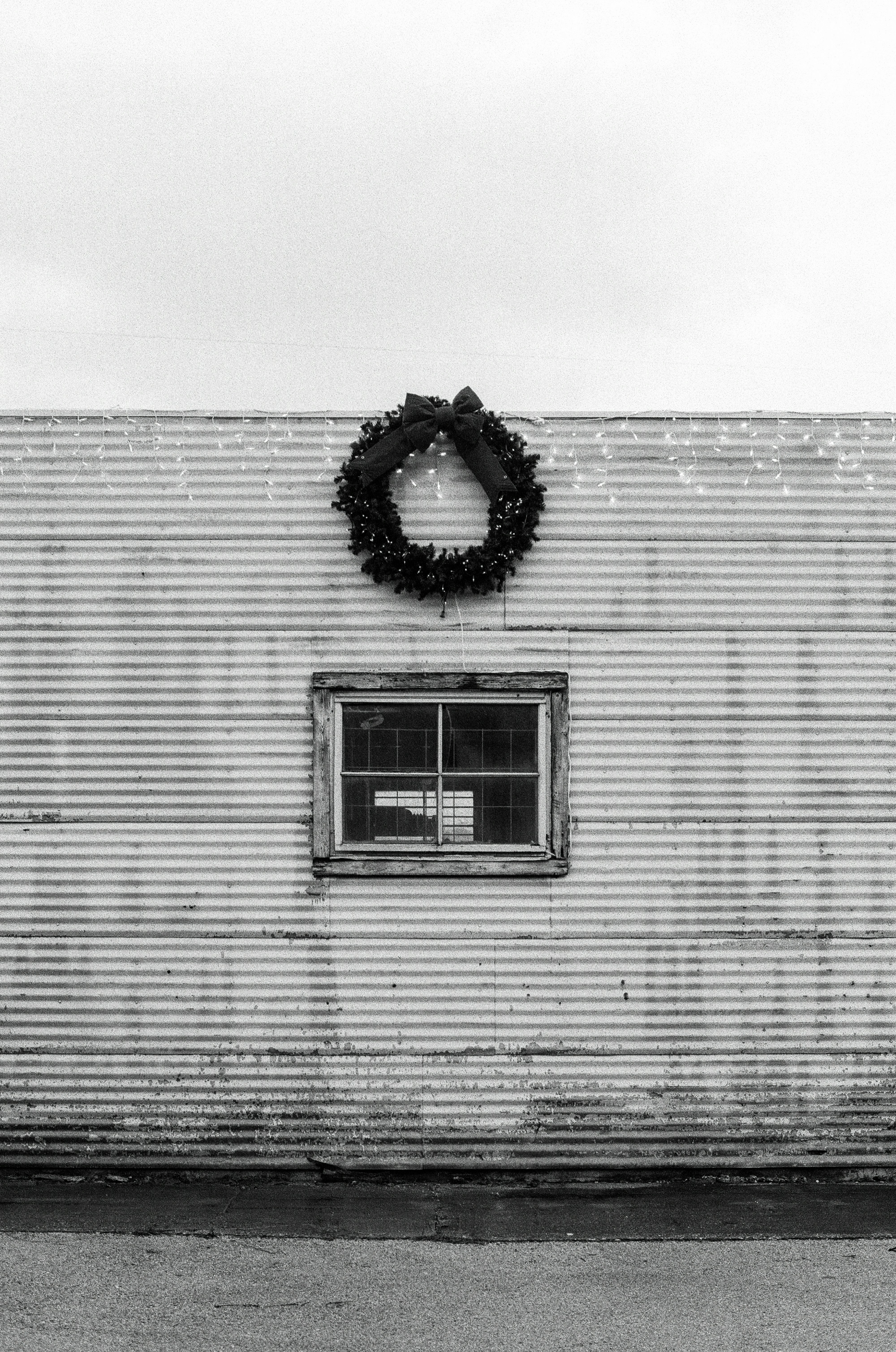 Photo of Wreath hanging above a window on corrugated wall by Phil Harvey