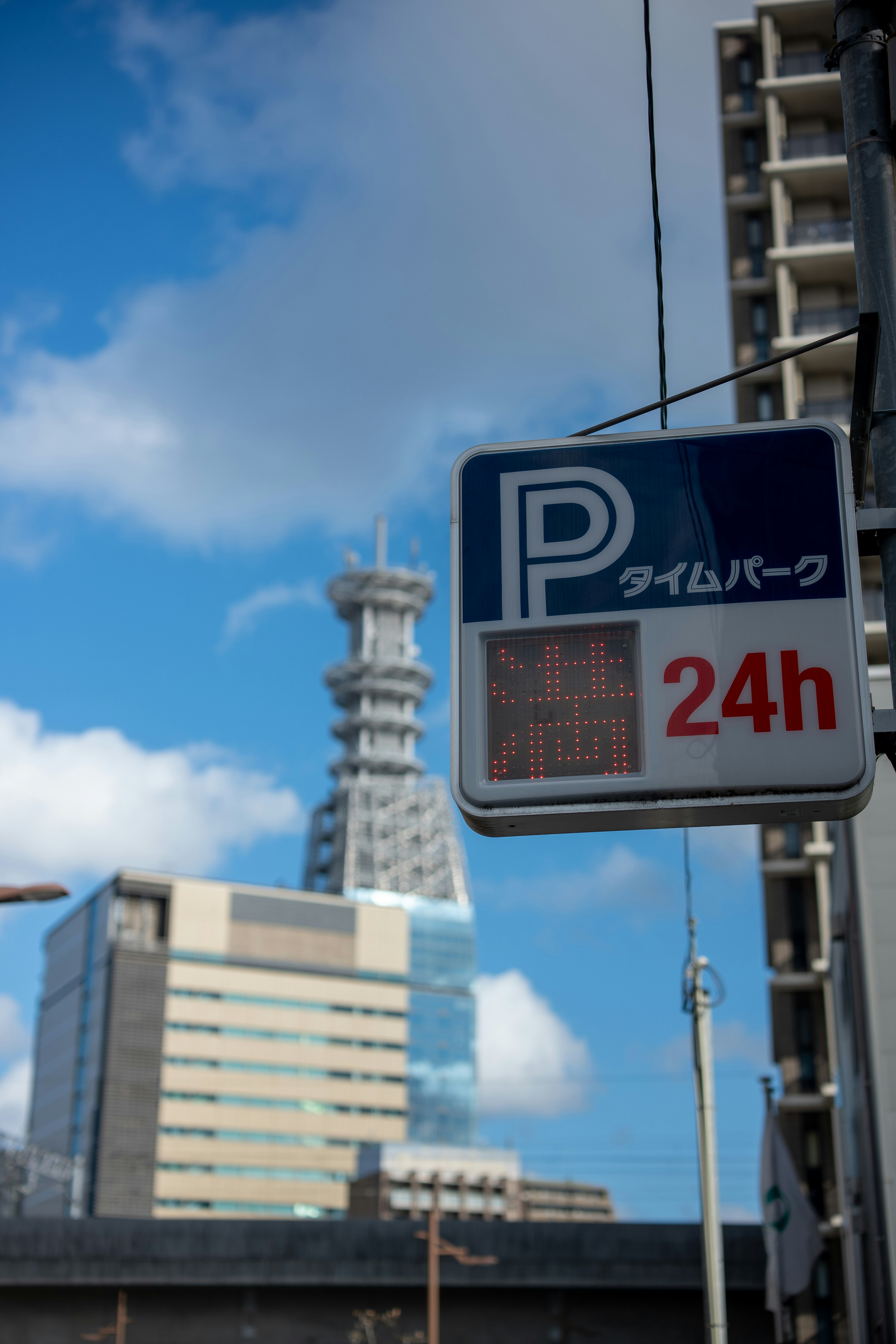 Parking sign with building and tower in background.