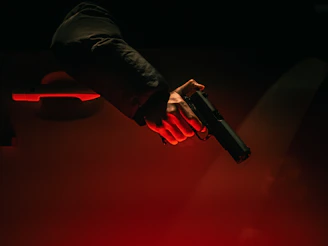 Hand holding a gun near a car door