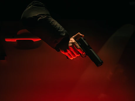 Hand holding a gun near a car door