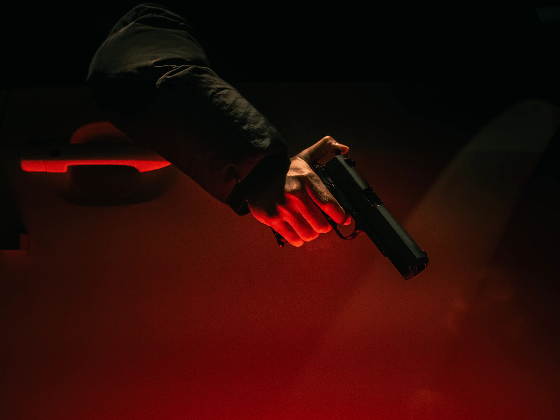 Hand holding a gun near a car door