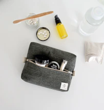 Gray toiletry bag with travel-sized cosmetics and full-sized products.
