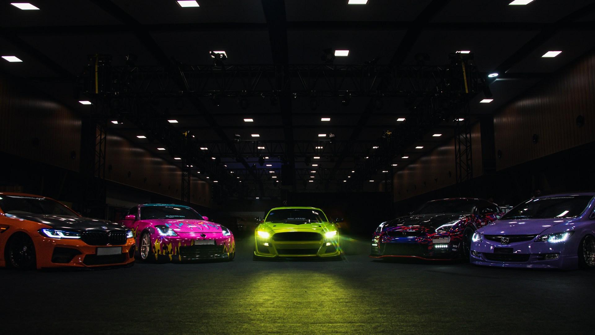 Five colorful sports cars parked in a dark garage.