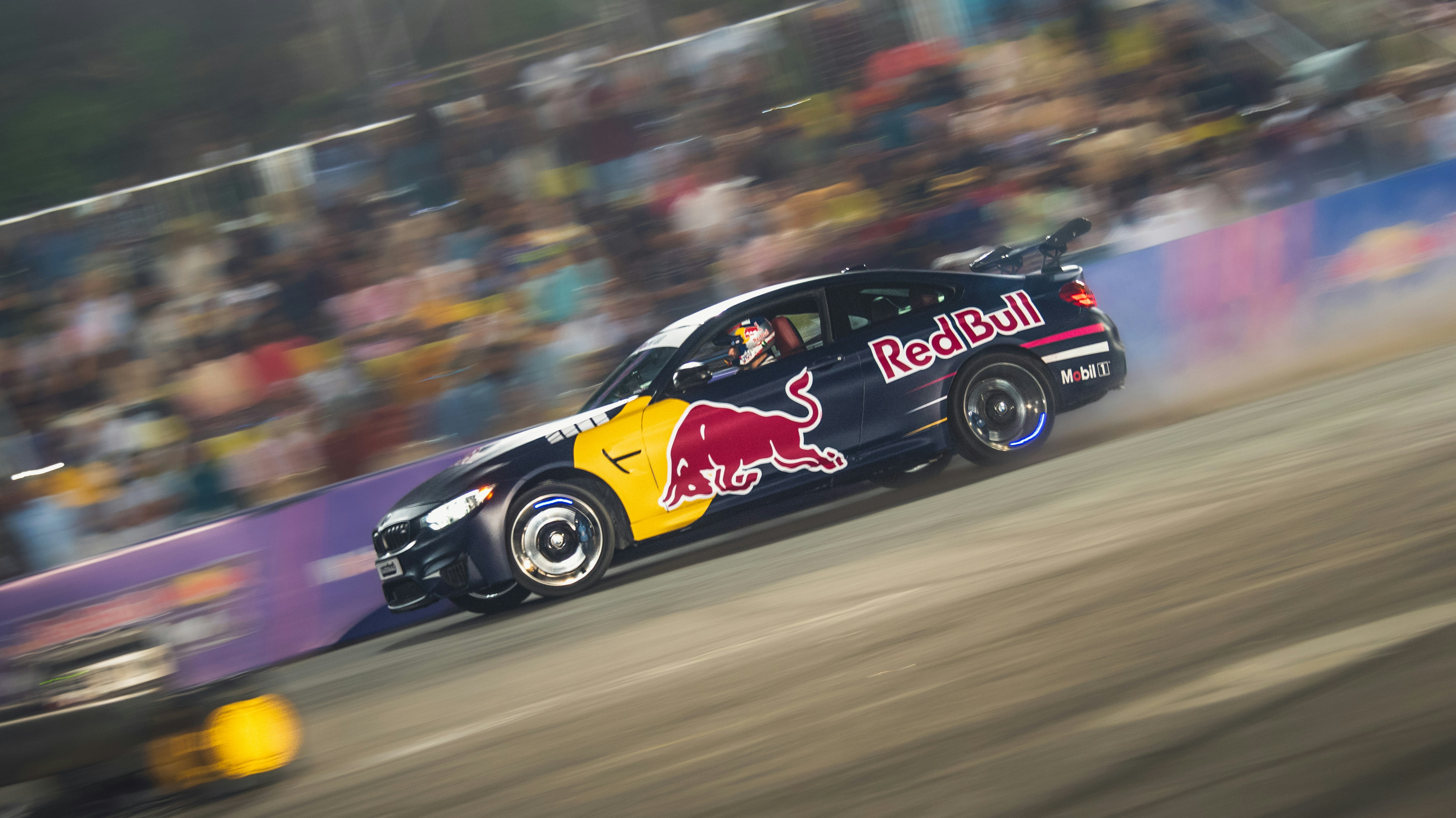 Voiture de course avec les logos Red Bull qui dérape sur la piste