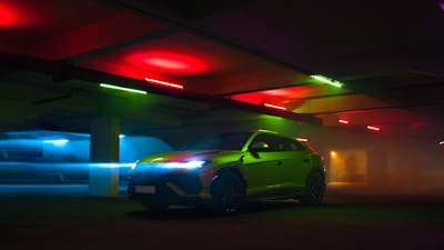 Green luxury suv parked under colorful lights.