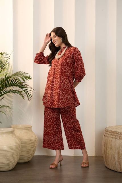 Woman in a patterned red outfit with statement necklace