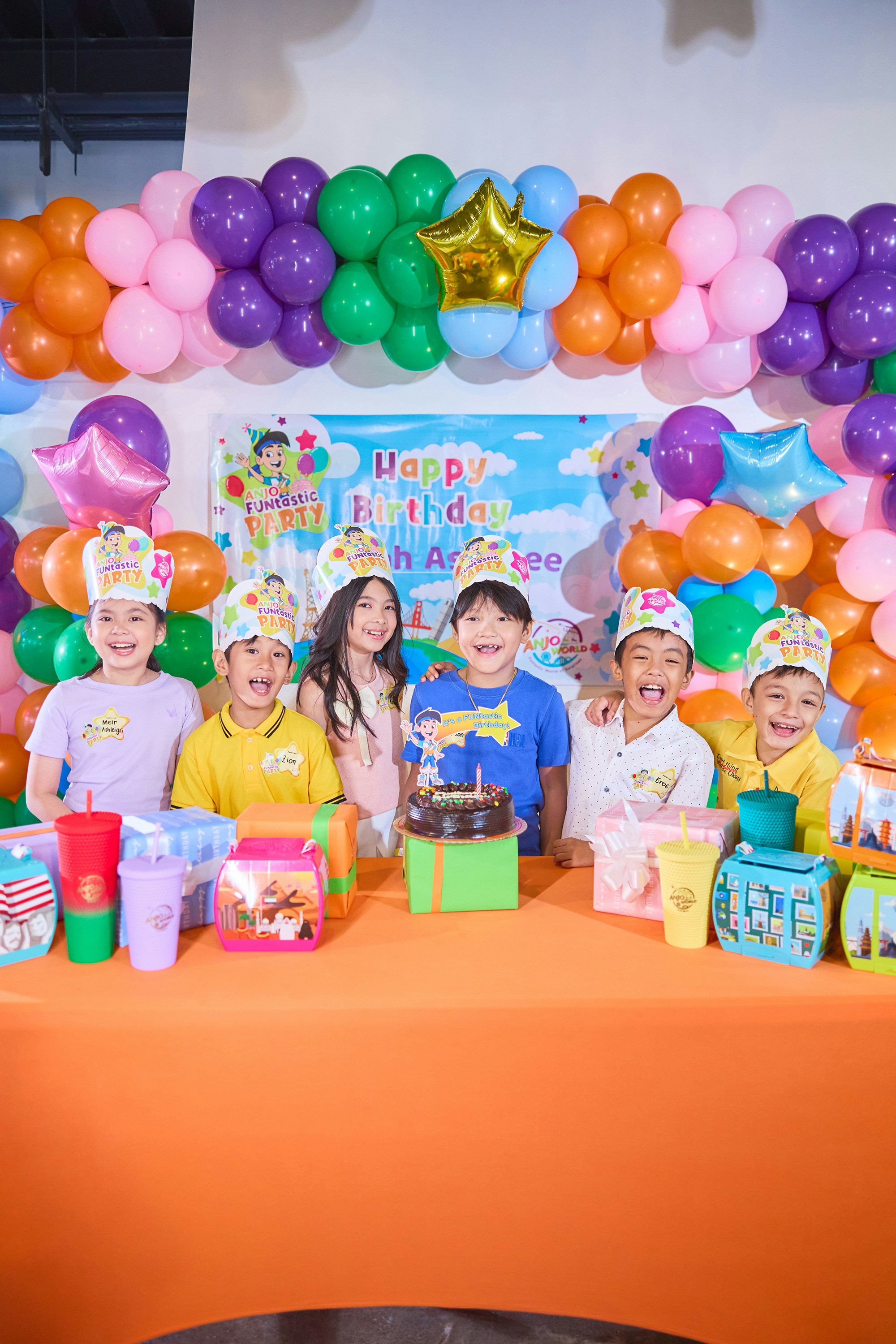 Happy group celebrating a birthday party with balloons and cake