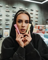 Woman in hoodie holds pink and yellow tubes