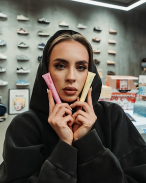 Woman in hoodie holds pink and yellow tubes