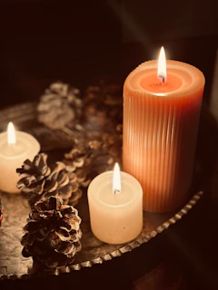 Three lit candles with pinecones on a tray