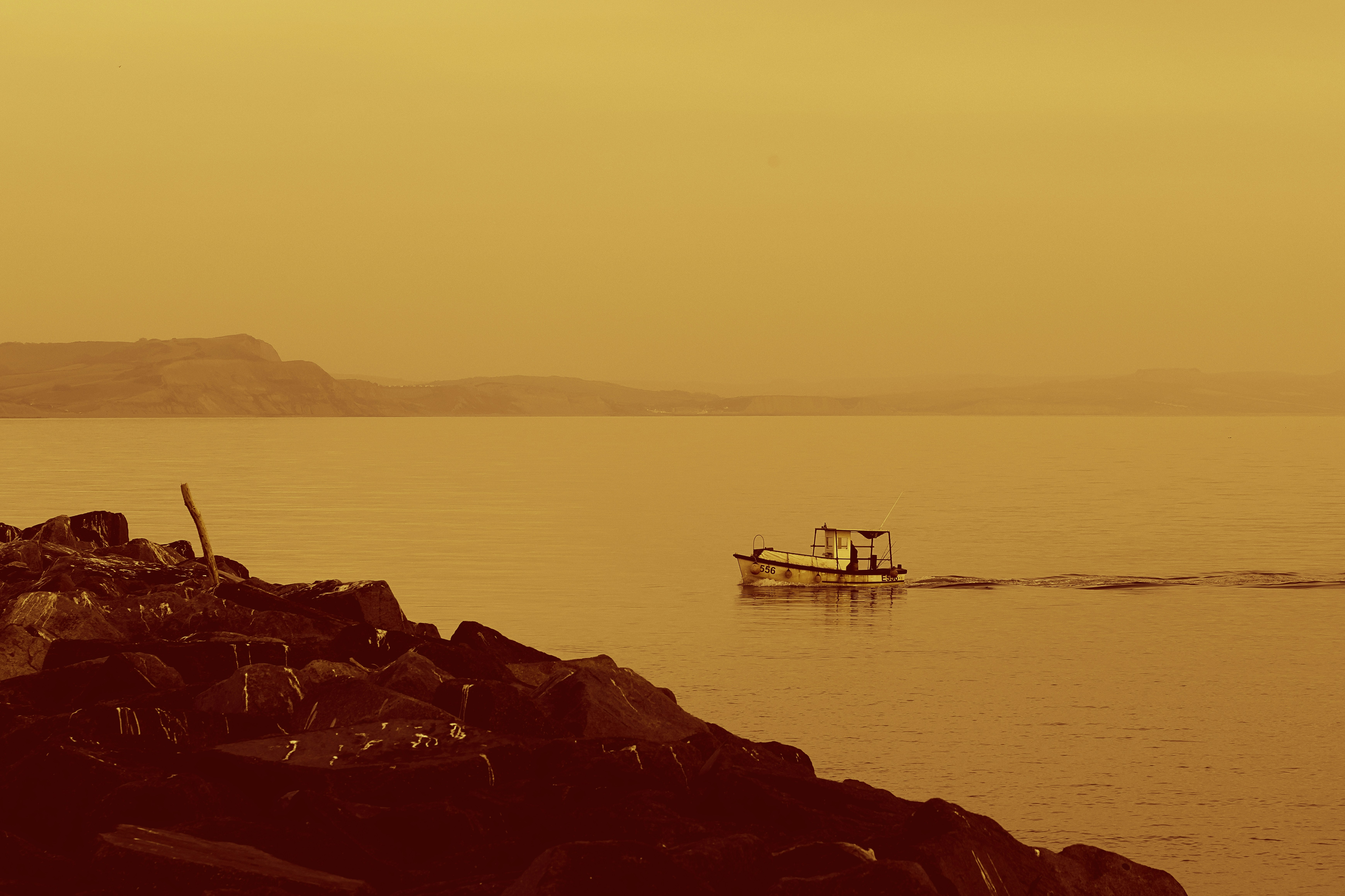 A small boat sails on a calm sea.