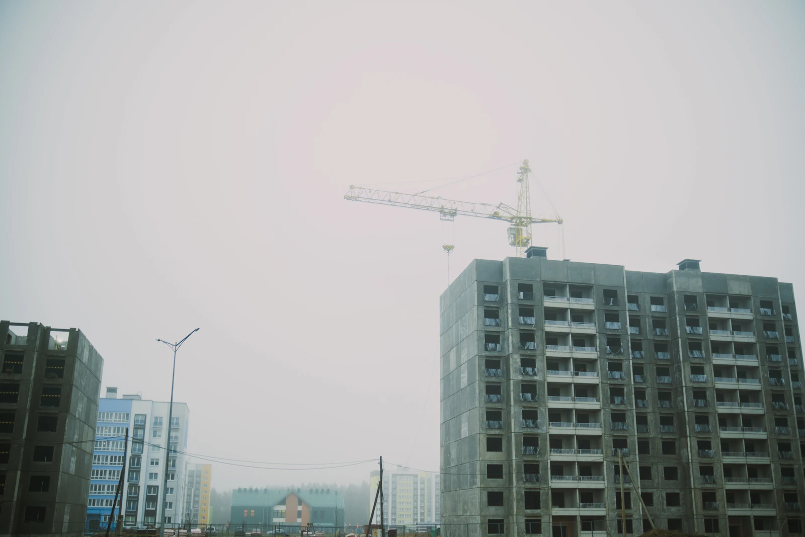 Unfinished apartment buildings with tower crane at a real estate construction site