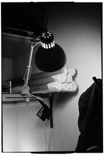 Desk lamp illuminates rolled papers on shelf.