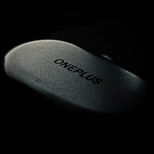 A dark gray oneplus computer mouse on black background