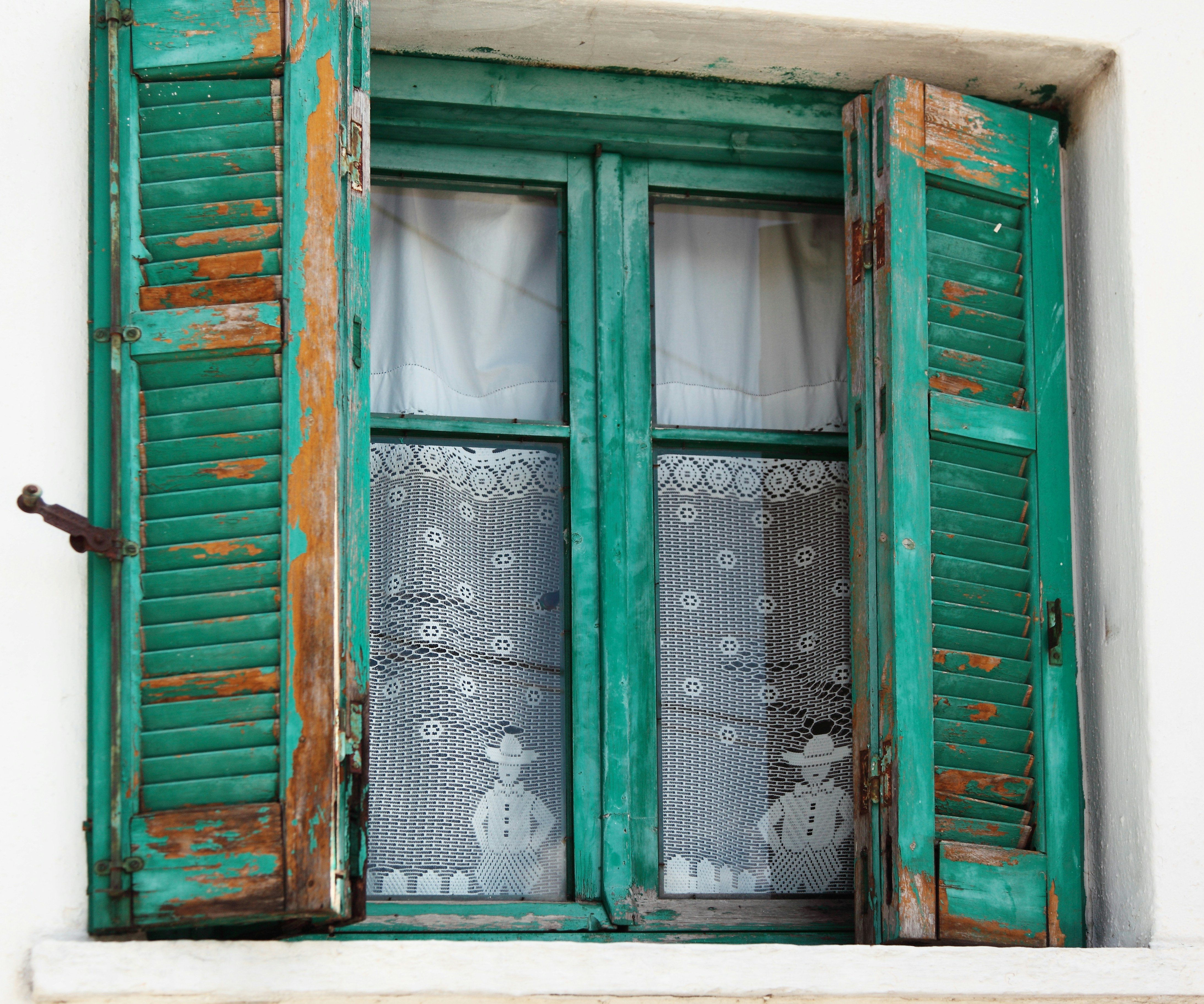 Old green shutters on a white wall