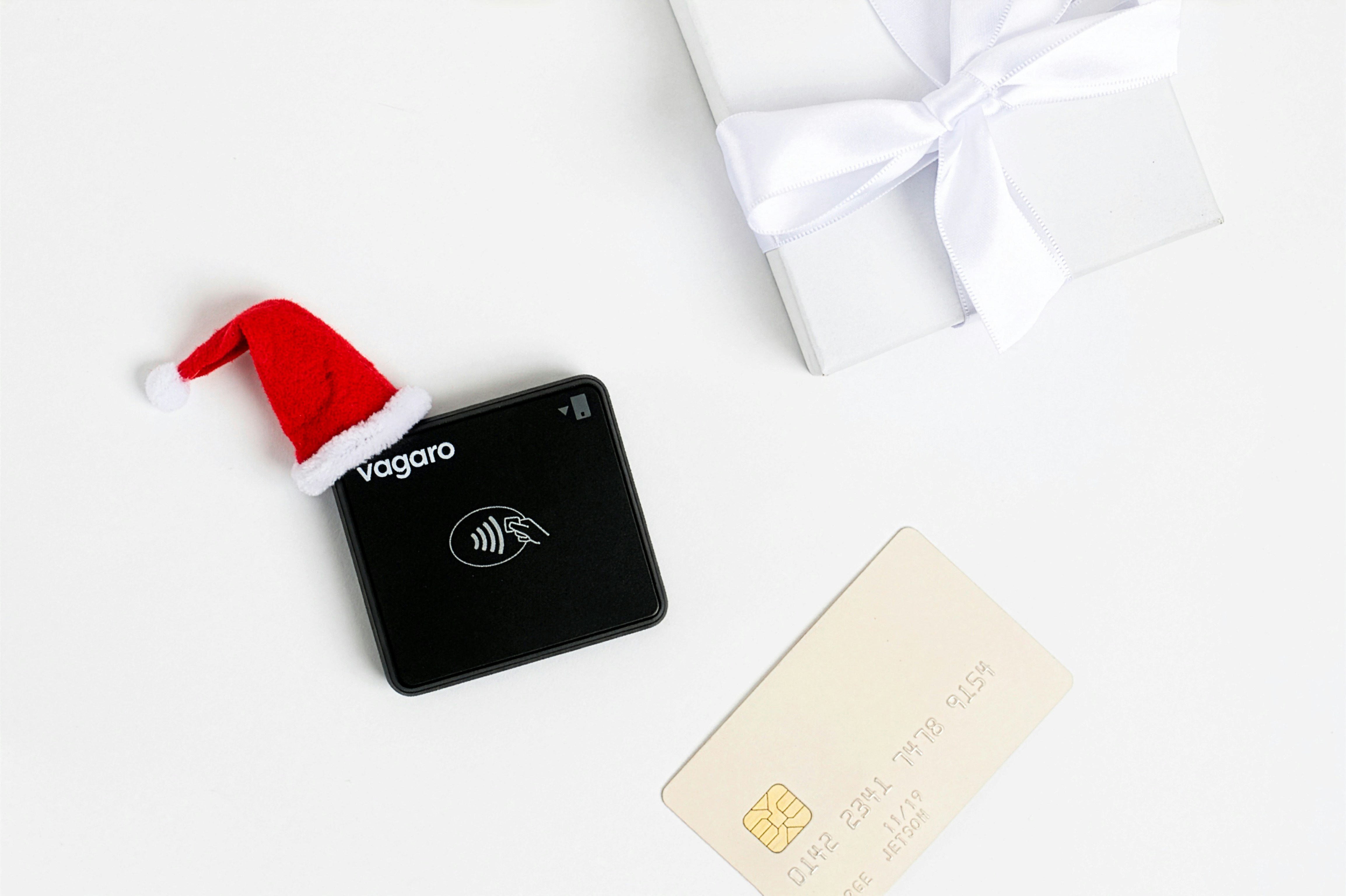 Black payment terminal with santa hat and gift.
