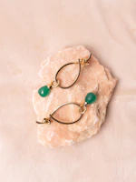 Gold earrings with green gemstones on pink stone