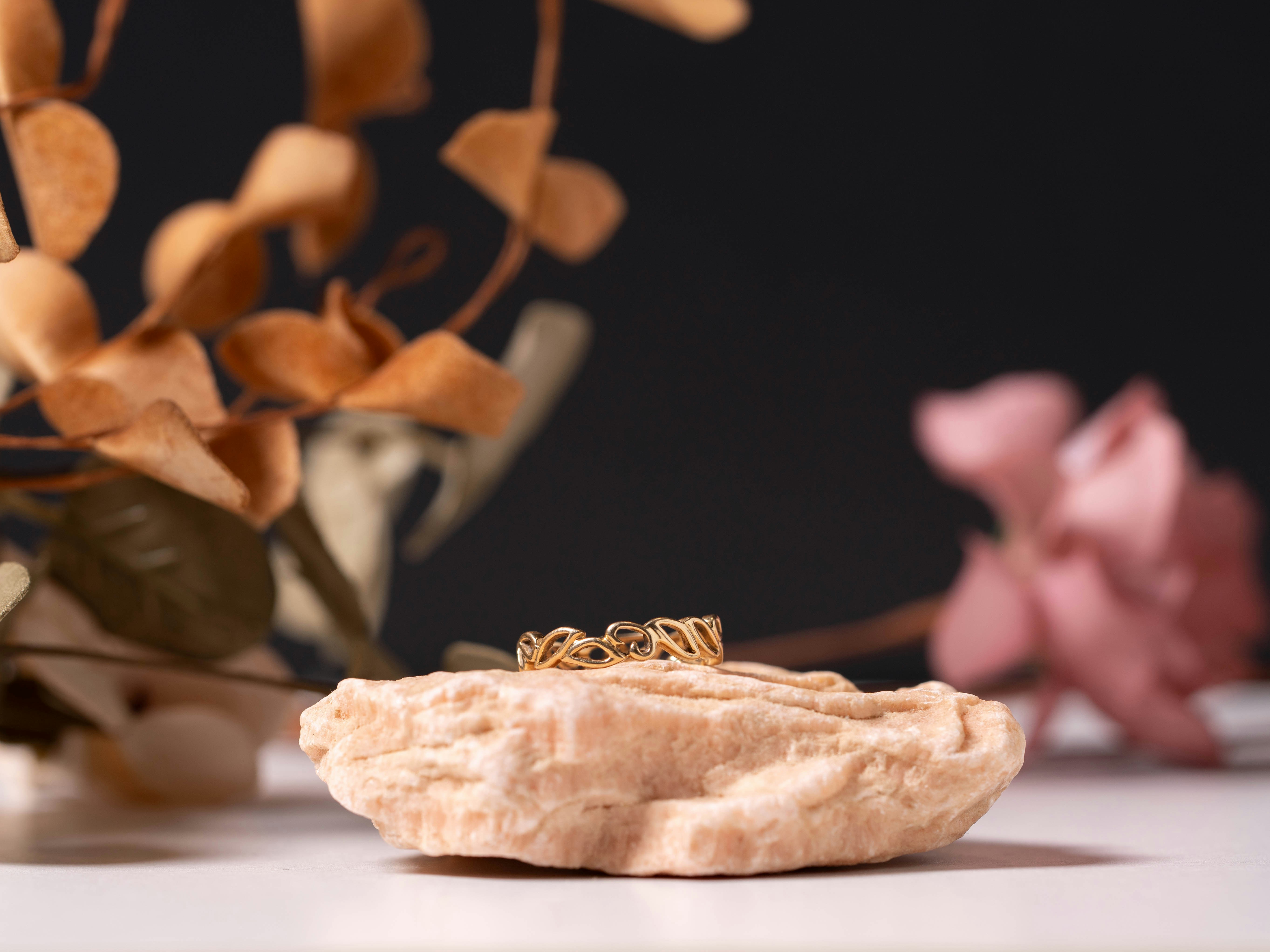 A ring rests on a textured rock with flowers.