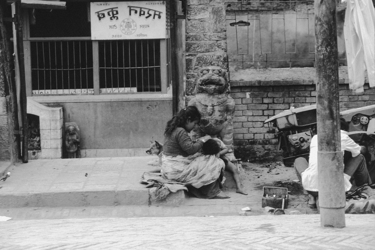 A woman and child sit on steps outside a store, symbolizing community connection for MLK Day volunteer projects.