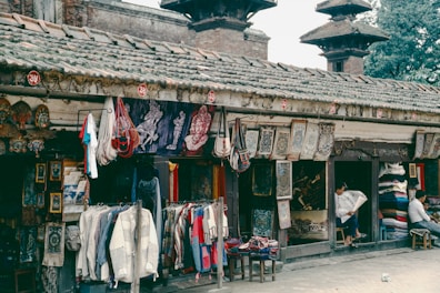 Outdoor market stall with hanging textiles and goods.