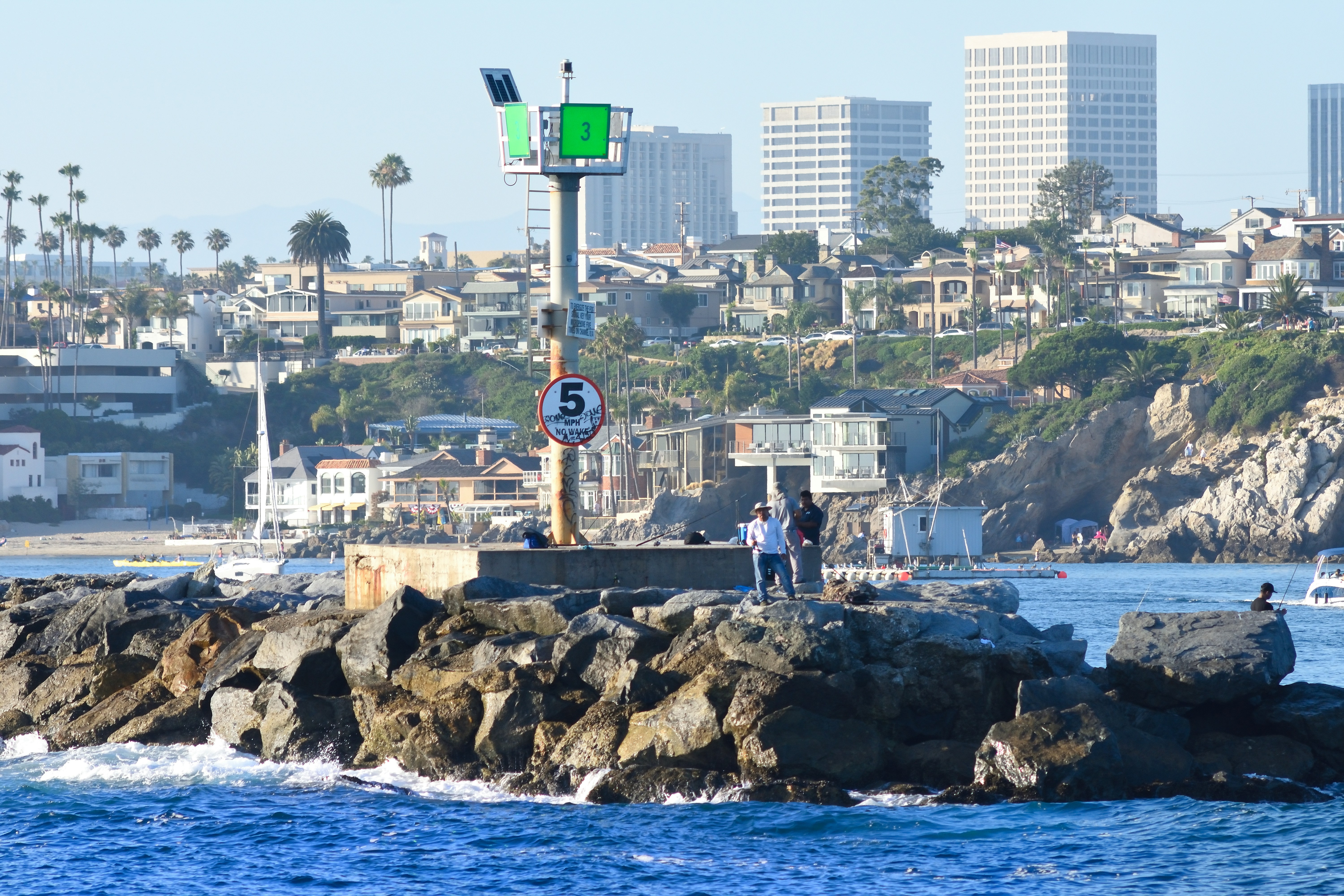 Marcador de navegação no píer rochoso com o horizonte da cidade.