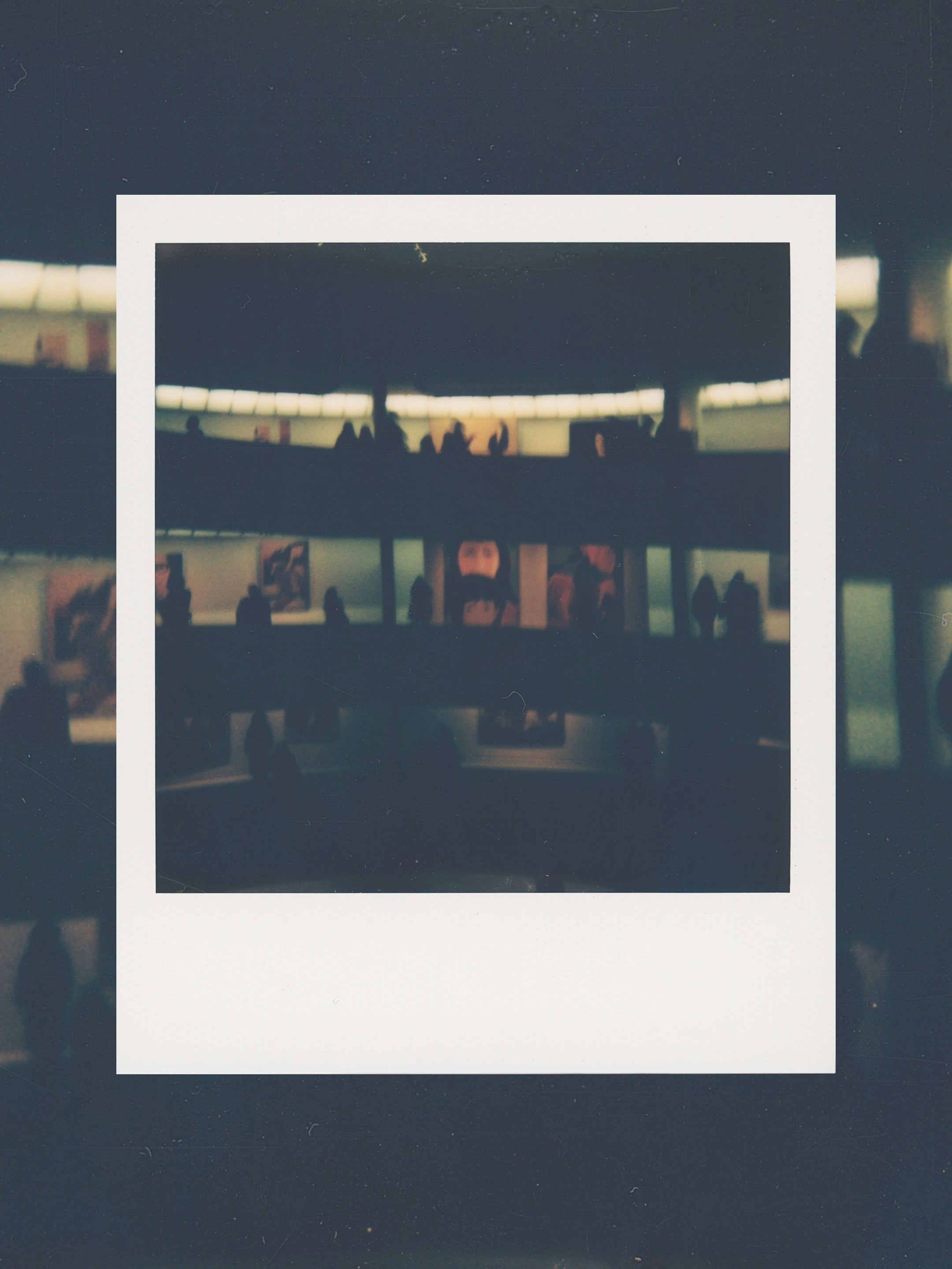 Silhouettes of people on a balcony in a museum.