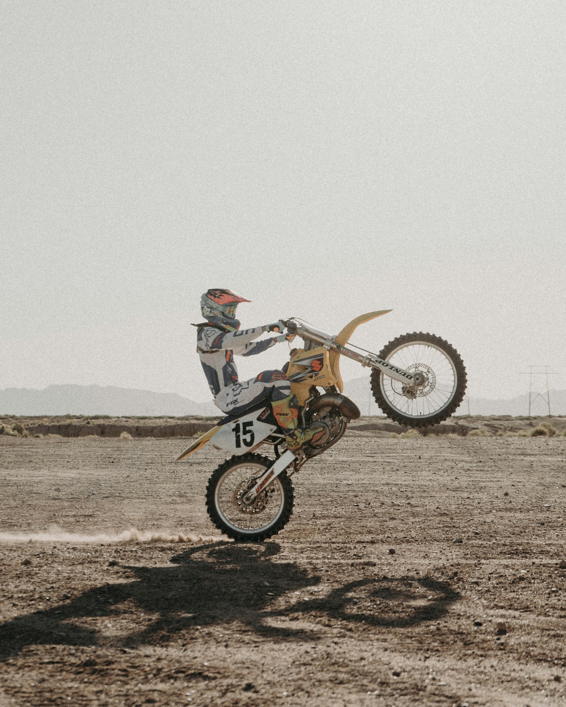 Motocross rider performing a wheelie in a desert