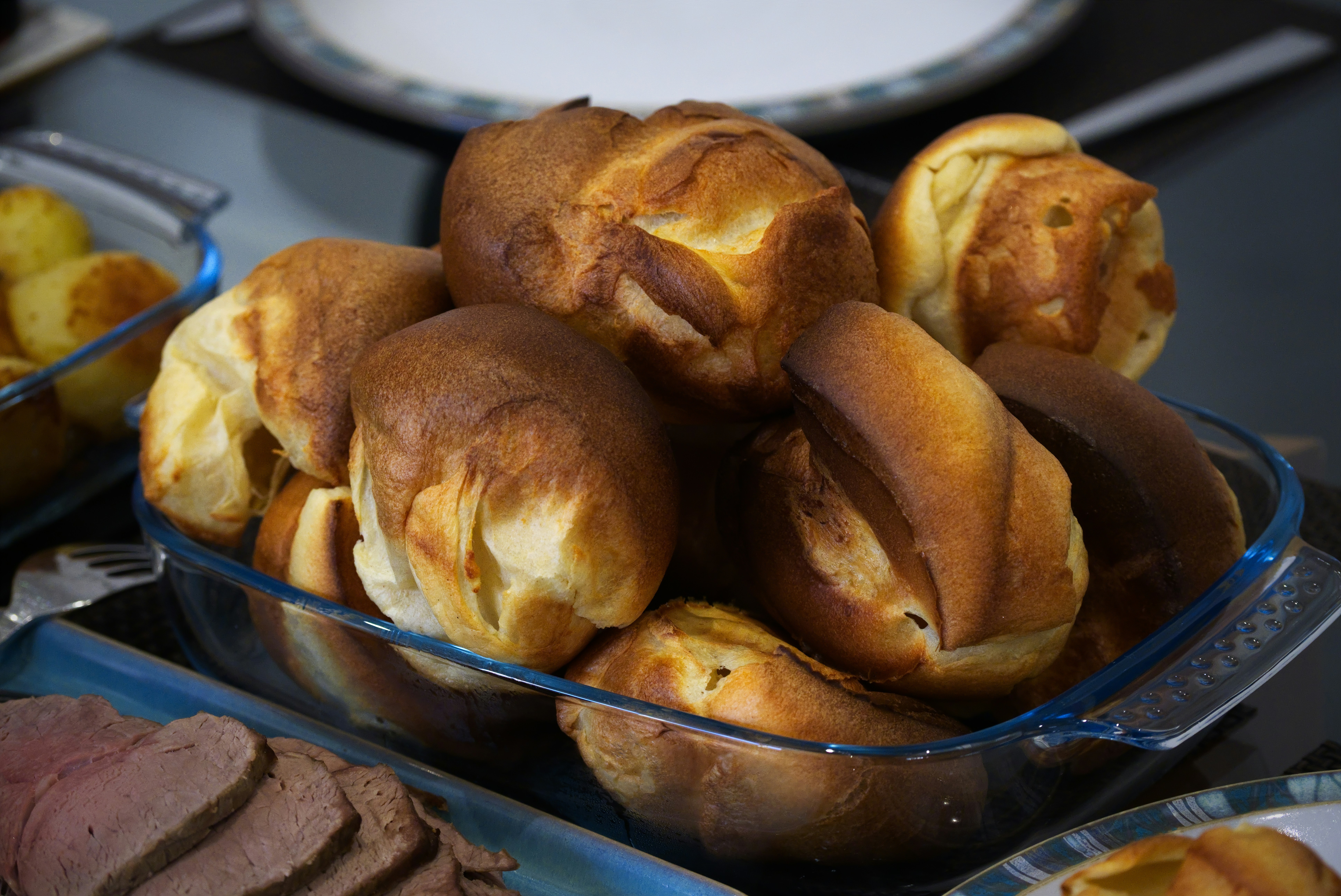 Golden brown yorkshire puddings in a glass dish.