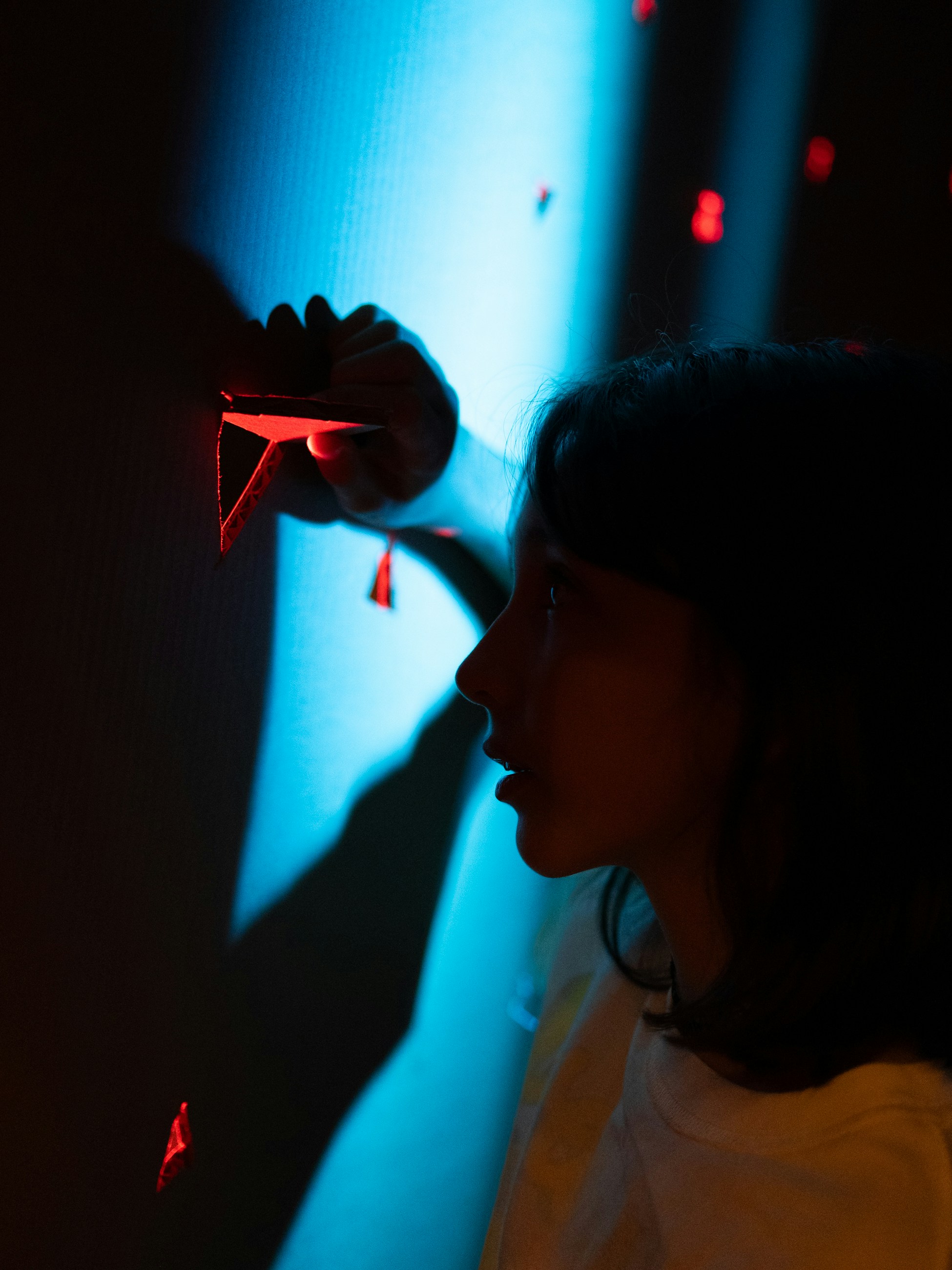 Woman reaching for red geometric shapes on wall.