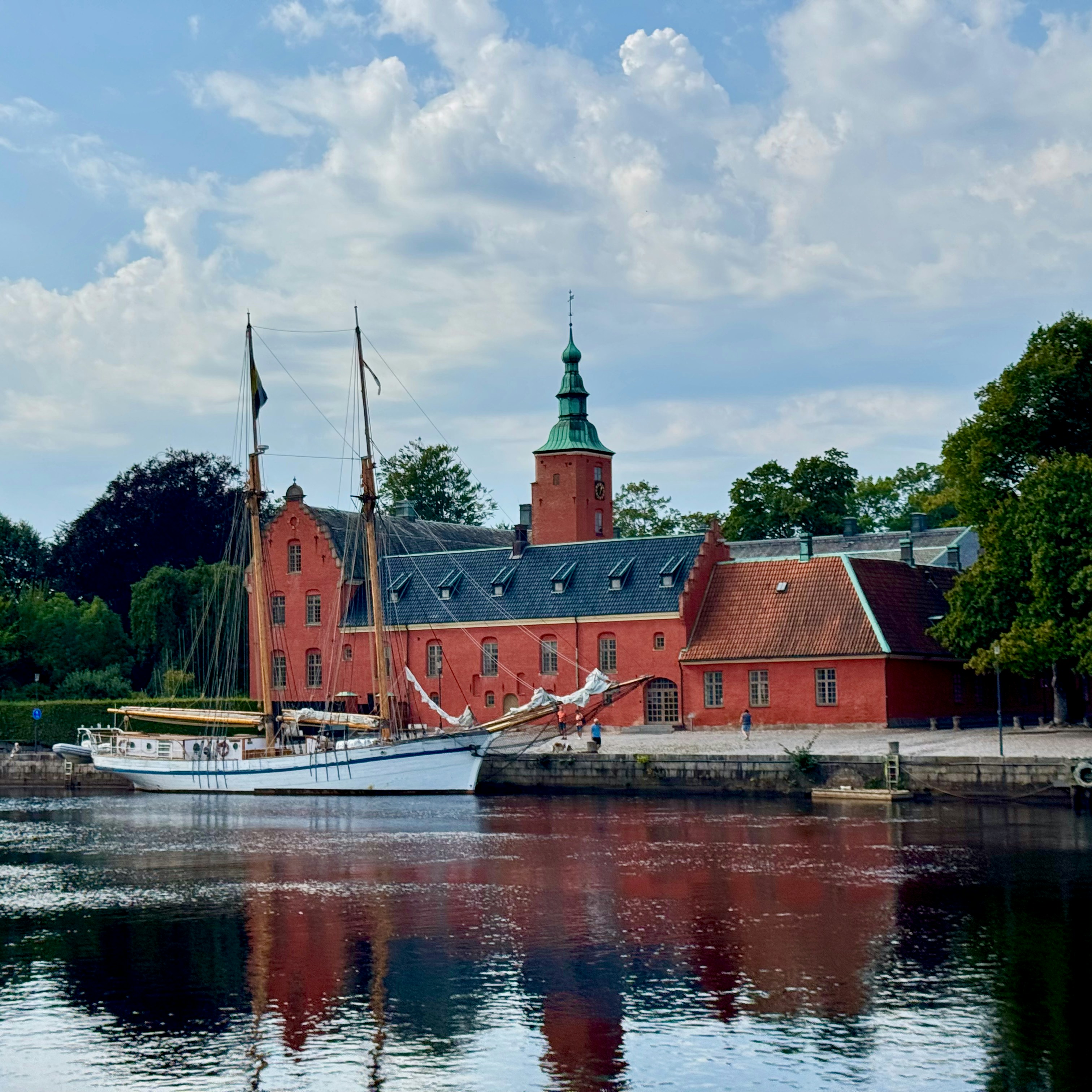Red brick building with a sailboat docked nearby.