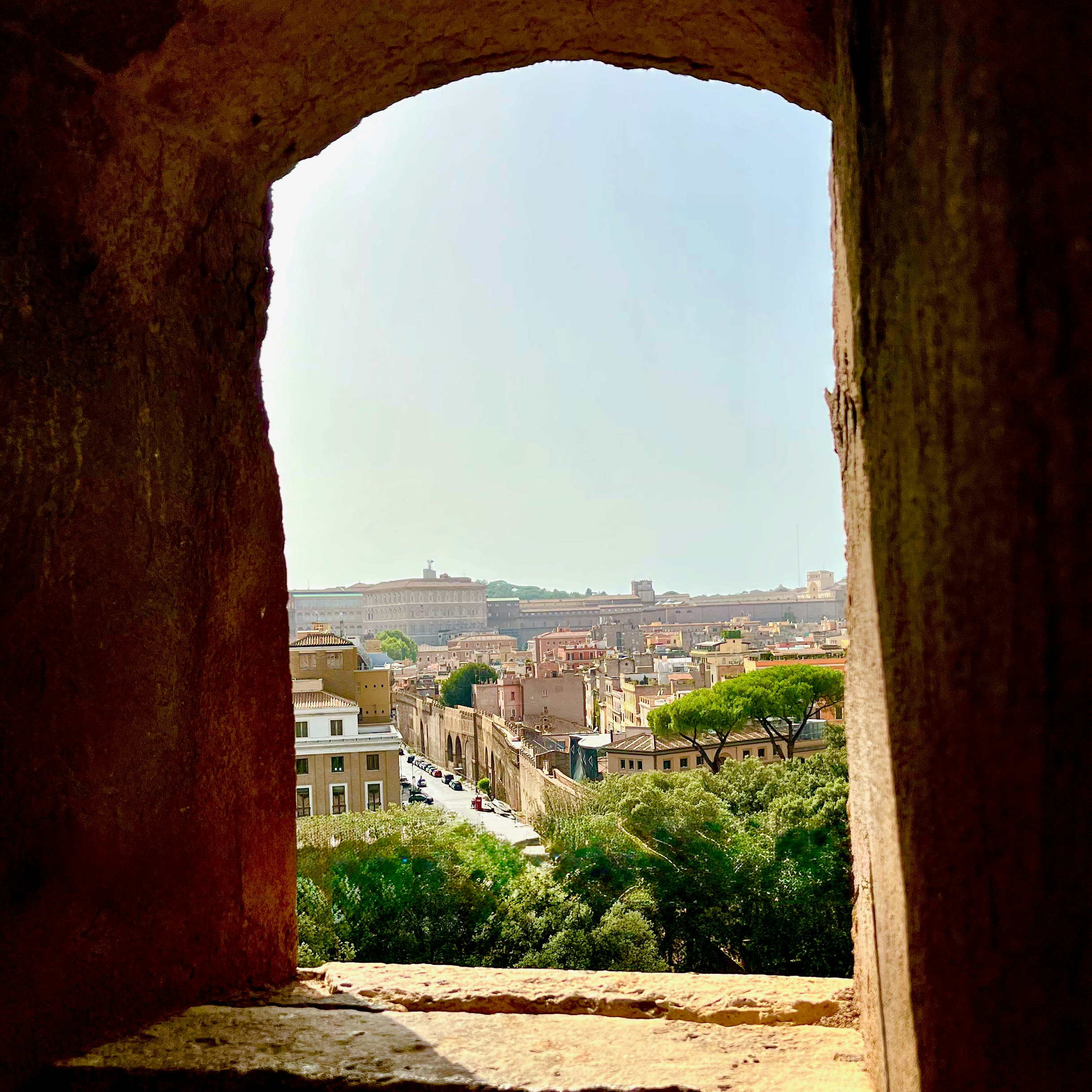 View of a historic city through an arched stone window.