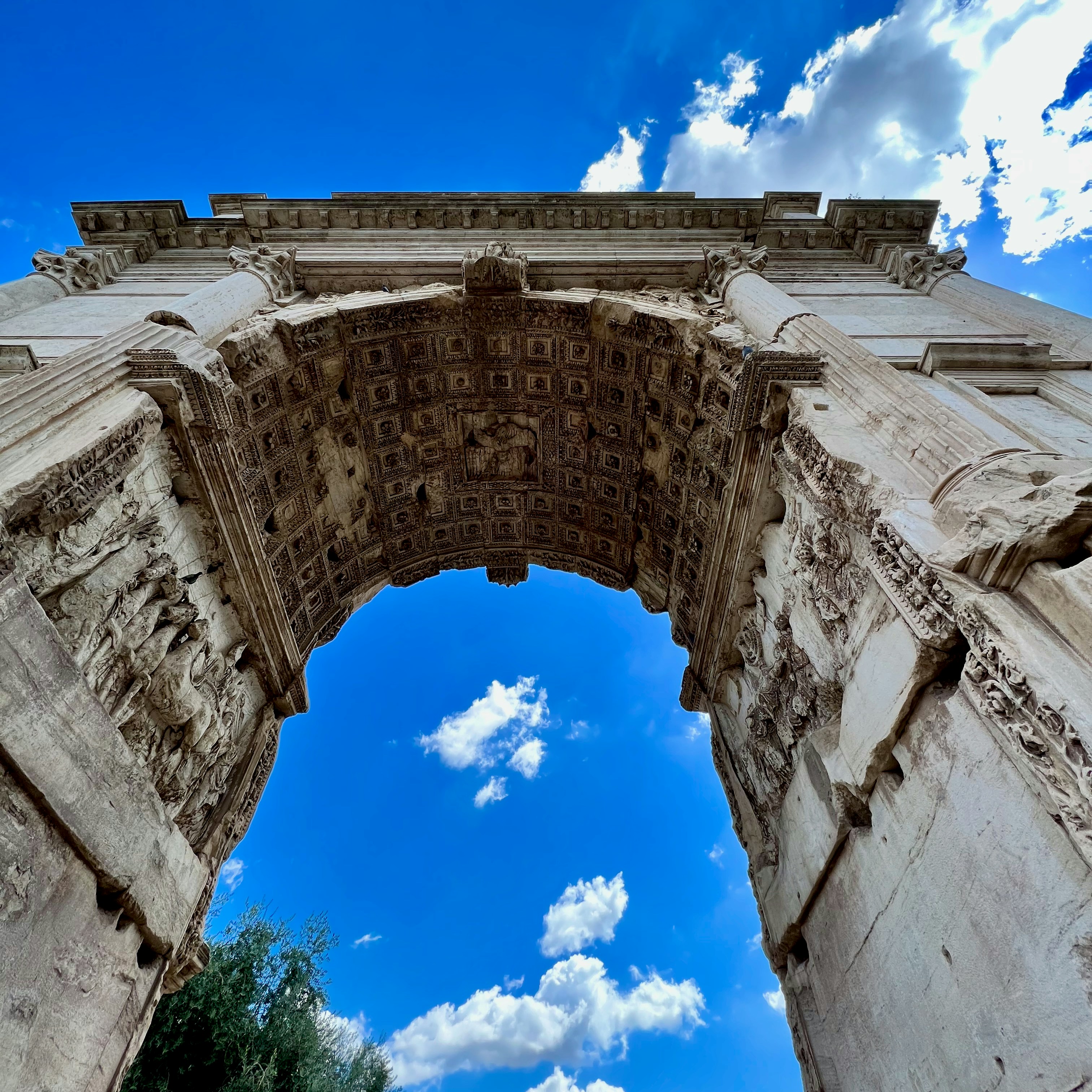 Arches of ancient roman ruins against blue sky.