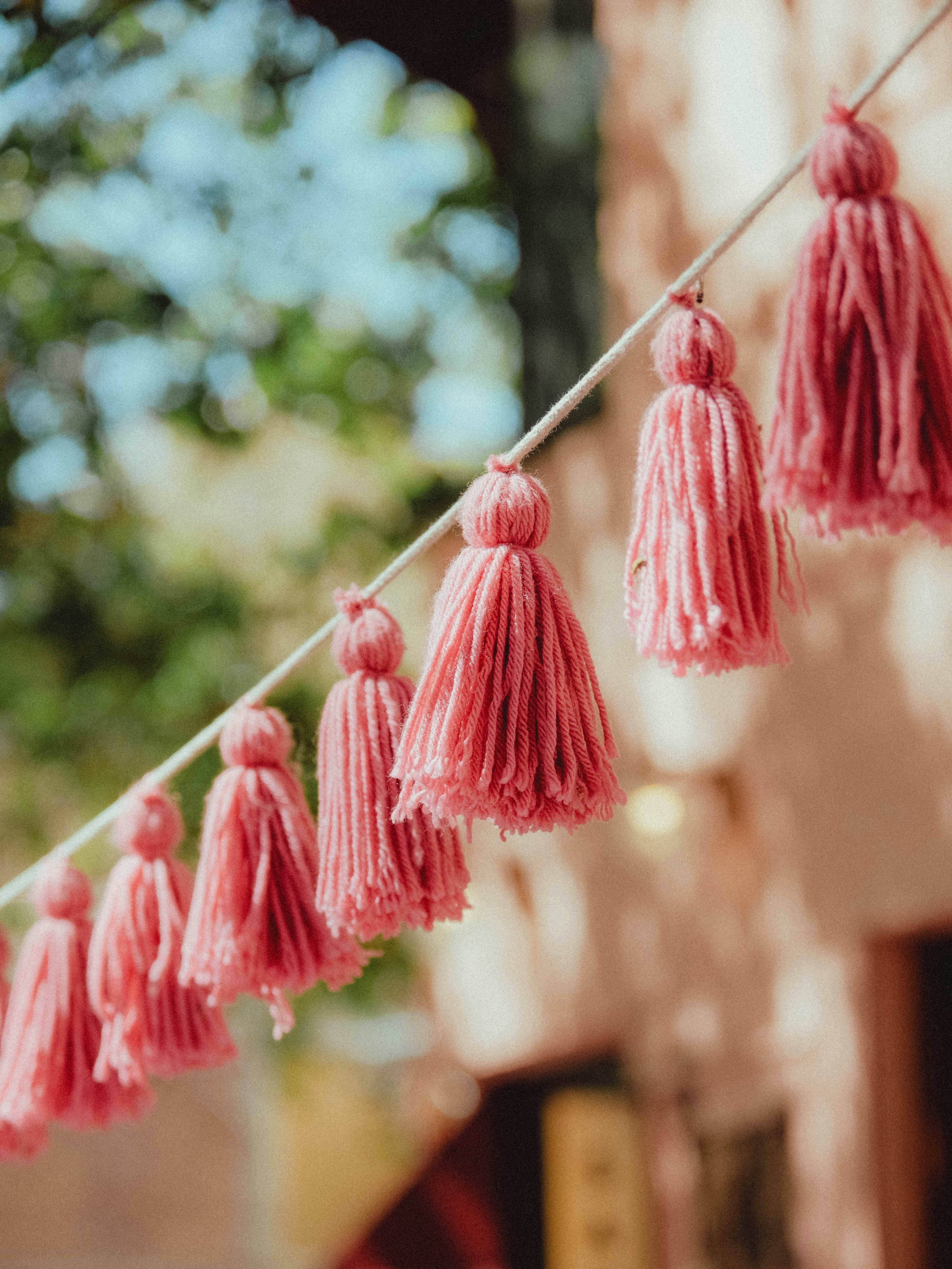 Pink yarn tassels hanging on a string outdoors