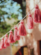Pink yarn tassels hanging on a string outdoors