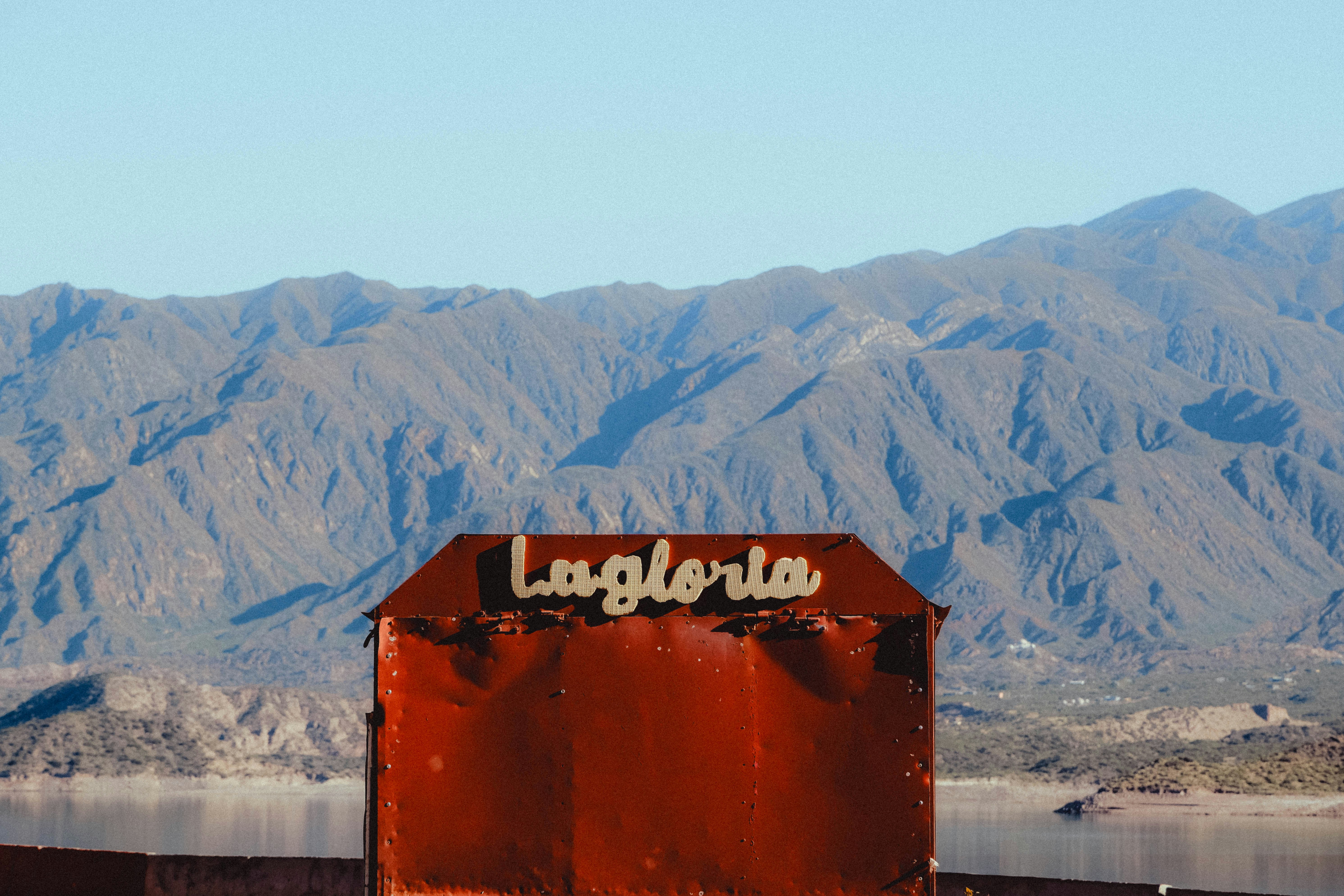 Rusty sign with "la gloria" against mountains