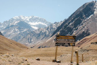 Wooden signpost in a mountain valley with snowy peaks